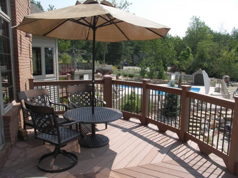 Custom built decks are tailored to your style and complement your home's structure. A rounded, composite deck overlooks a pool area and landscaping.