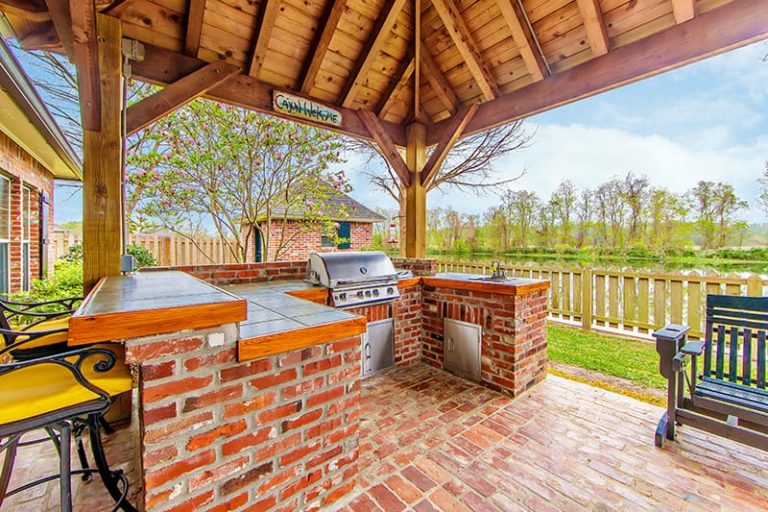 Building an outdoor kitchen is a challenge, but it can be very rewarding. An outdoor kitchen with a built-in grilling space and added bar top. Brick themed under a cathedral canopy.