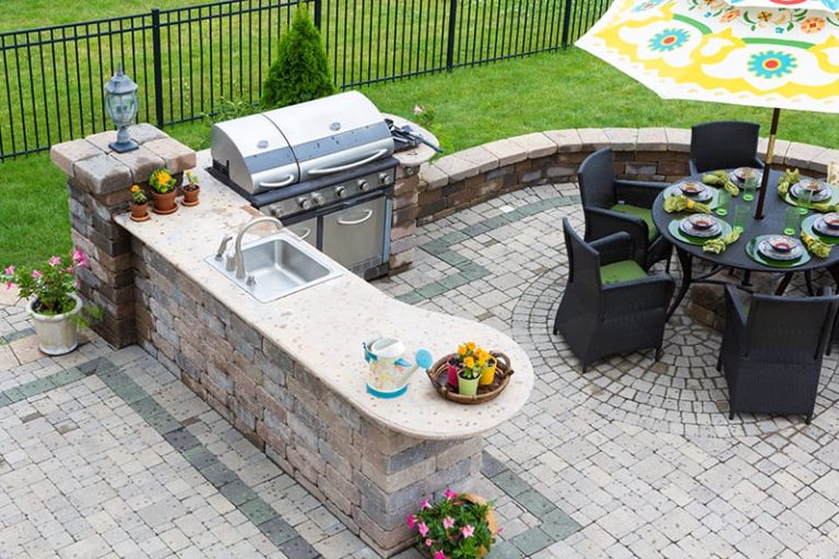 A bird's eye view of an outdoor cooking area, complete with grilling and serving stations on a paver patio.